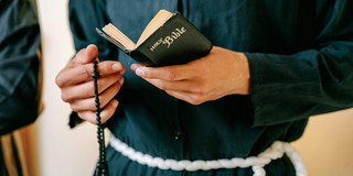 Close-up of a monk reading the Bible and holding a rosary.