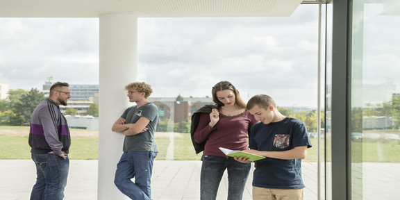 Studierende im Gespräch vor einem Fenster