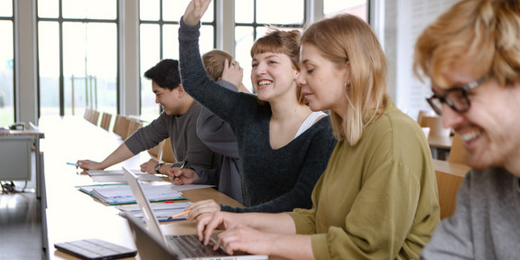 Students in seminar_04 Five students sitting in the seminar room at the table. A female student raises her hand.